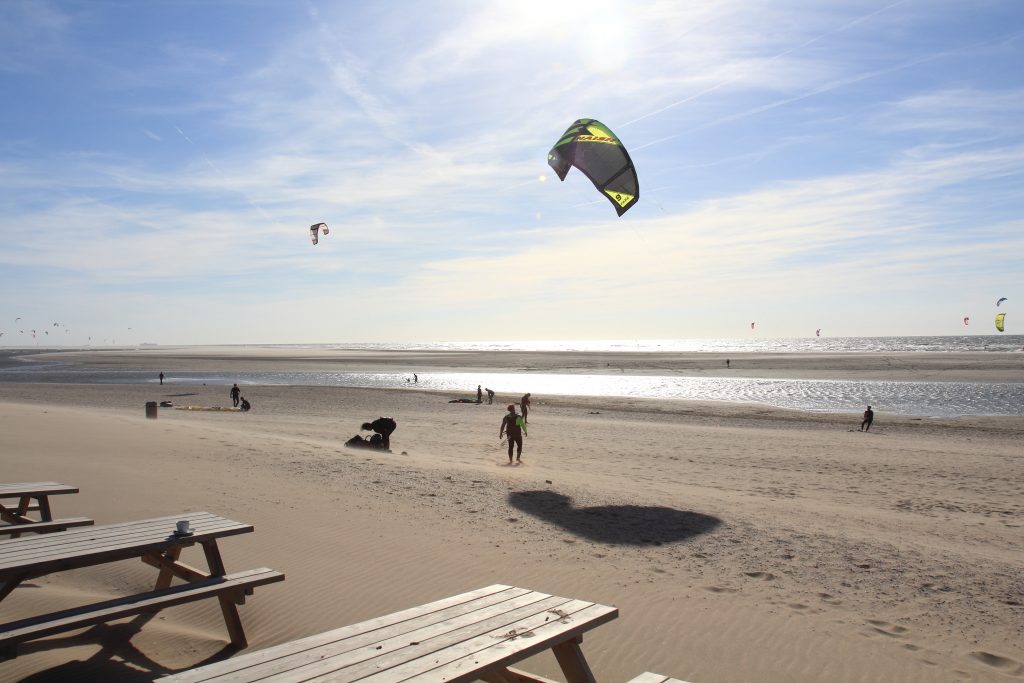 Afbeelding van een kitesurfer op het strand bij de zandmotor.